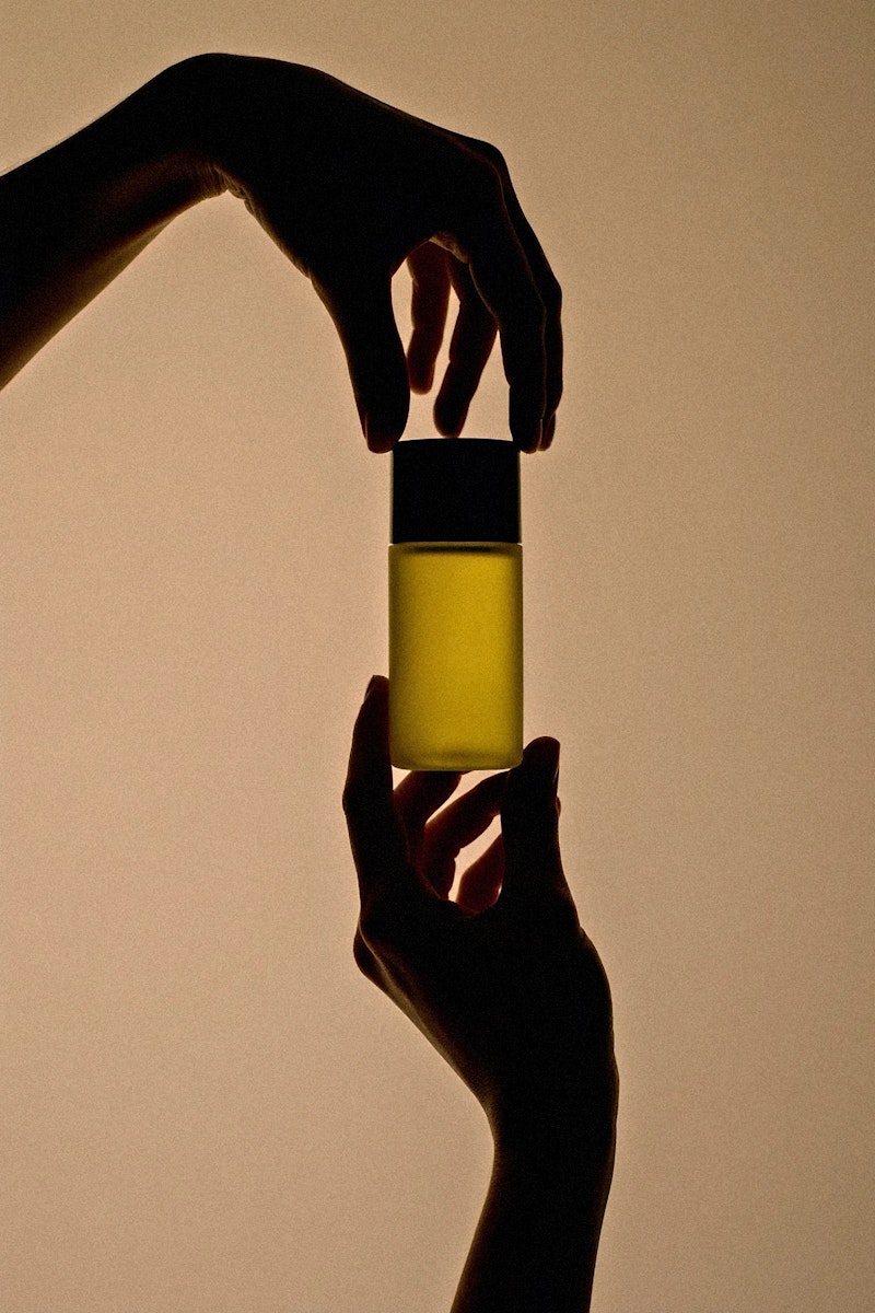 Creative product photography for Marrakech Oil's pure argan oil, with the bottle appearing to float between two hands, symbolizing a gentle touch.