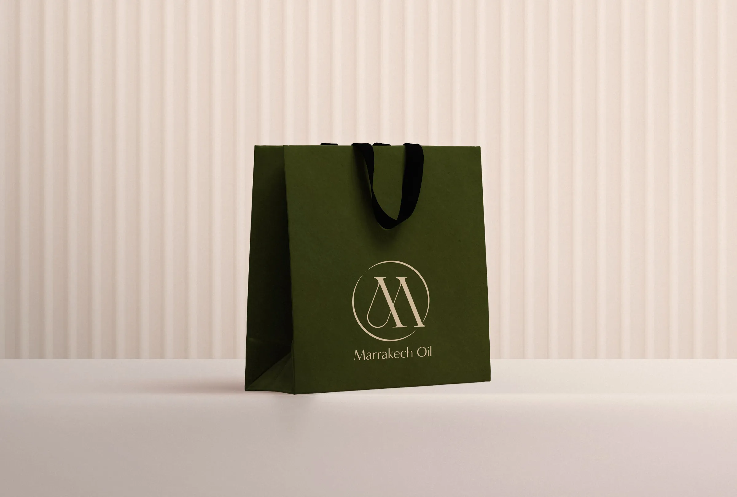 A dark green luxury retail bag for Marrakech Oil, showcasing the elegant brand logo. An example of premium skincare packaging design."
