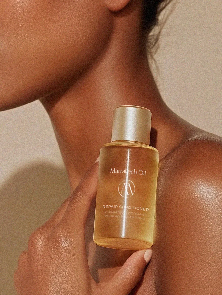 A lifestyle image featuring the Marrakech Oil serum on a marble vanity, representing a luxury skincare brand aesthetic.