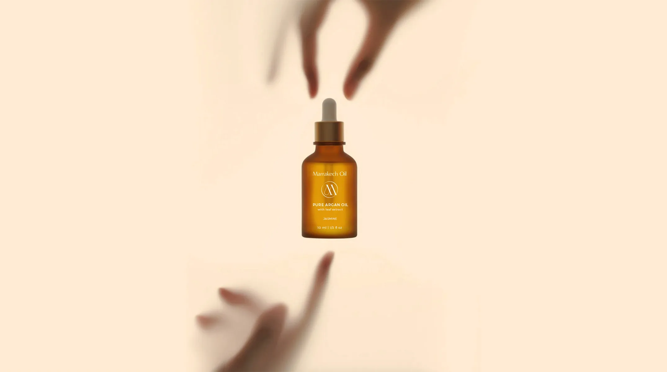 Creative product photography for Marrakech Oil's pure argan oil, with the bottle appearing to float between two hands, symbolizing a gentle touch.