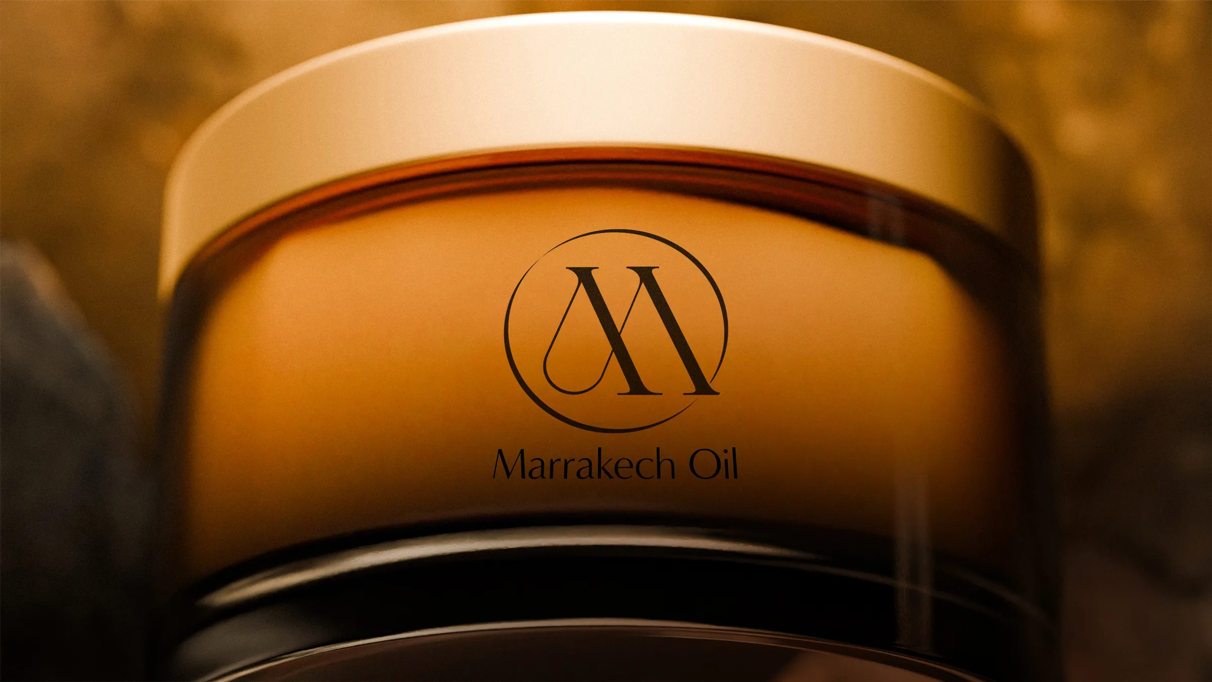 A close-up detail of the Marrakech Oil logo on a luxury skincare jar, demonstrating clean and minimalist cosmetic branding.